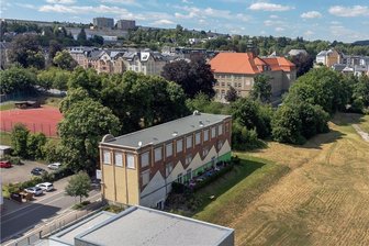 Auerbach lässt Altenheim bauen: Droht danach ein Überangebot? - Schon im vorigen Jahr hat die Stadt 9400 Quadratmeter des ehemaligen Wema-Geländes an die Theed Auerbach GmbH veräußert. Nun bekommt der Chemnitzer Investor noch das 4000 Quadratmeter große Nachbargrundstück. Ein Seniorenzentrum mit 150 Plätzen soll entstehen. Vorn im Bild das Dach des Neuapostolischen Gotteshauses, links das Familienhotel im ehemaligen Wema-Verwaltungsgebäude, dahinter die Geschwister-Scholl-Schule