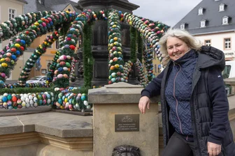 Auf Osterbrunnen-Tour durchs Erzgebirge - Nach der Premiere 2025 ziert auch in diesem Jahr wieder eine Osterkrone den Uthmann-Brunnen in Annaberg-Buchholz. Ivonne Schröter vom Werbering hat die Dekoration gemeinsam mit Bauhofmitarbeitern aufgebaut.