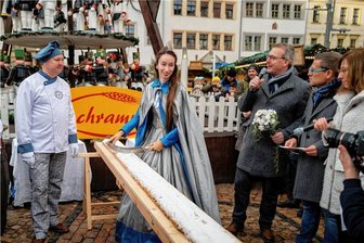 Auftakt für erstes Adventswochenende in Freiberg: Riesenstollen auf dem Christmarkt ist angeschnitten - Silberstadtkönigin Celine (Mitte) schnitt zusammen mit Oberbürgermeister Sven Krüger (parteilos, 3. von rechts) und Bäckermeister René Buschmann (links) den Stollen auf dem Freiberger Obermarkt an.