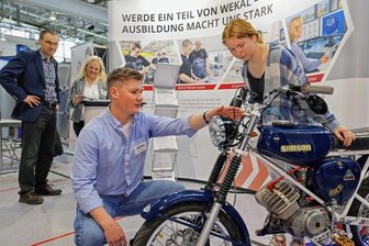Ausbildungs- und Jobbörse in Glauchau: Simson wirbt für Maschinenbau - Bei der Ausbildungsmesse in Glauchau war die Simson am Stand von Wekal ein besonderer Hingucker. Lenja Grenz (rechts) lässt sich die Raffinessen des Mopeds von Hans Mucke erklären. Im Hintergrund Wekal-Prokurist Peter Kretschmer und Personalchefin Katja Roder.