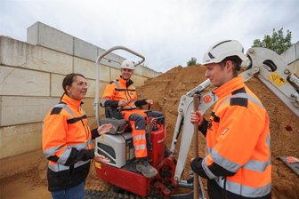 Ausgezeichnet: Was Hüttner Bau in Chemnitz beim Nachwuchs richtig macht - Ein gutes Team bei Hüttner Bau: die Ausbildungsverantwortliche Stefanie Zauge, Jungfacharbeiter Lorenz Ehrlich auf dem Bagger und der angehende Betonbauer Tommy-Lee Pörner.