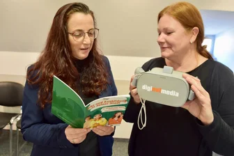 Ausstellerrekord bei Limbacher Ausbildungsmesse: Wie funktioniert die Jobsuche mit VR-Brille? - Simone Friedrich (links) mit der Broschüre und Nadine Dörfler mit einer der VR-Brillen, die bei der Messe angeboten werden.