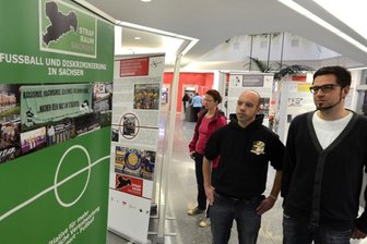 Ausstellung in Auerbacher Sparkasse widmet sich Hass am Spielfeldrand - In der Auerbacher Sparkasse ist seit Montag die Ausstellung über "Fußball und Diskriminierung in Sachsen" eröffnet worden, im Bild die Organisatoren Tobias Bahr (links) und Volker Herold vom Fanprojekt Plauen-Vogtland. Das Interesse der Besucher war von Anfang an groß. Schon am Mittwoch zieht die Schau nach Plauen weiter.