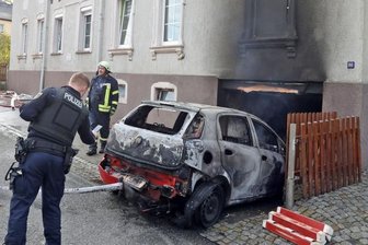 Auto brennt in der Garage aus - Einsatzkräfte der Feuerwehr ziehen das völlig ausgebrannte Autowrack aus der Garage des Hauses.