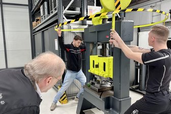 Azubis vom Porsche Werkzeugbau retten Grubenbahn im Besucherbergwerk Pöhla - Da staunt der Vereinschef vom Besucherbergwerk nicht schlecht, als Yannik Beyrich (r.) und Jonas Voike (hinten) zeigen, wie sie mittels Handdruckpresse das Teil formen.
