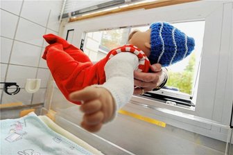 Babyklappe in Aue: Wie das Hilfsangebot genutzt wird - Eine Frau legt eine Babypuppe in eine Babyklappe. Das Foto zeigt ein Hilfsangebot in Karlsruhe (Baden-Württemberg), das 2001 startet. Seit 2009 gibt es auch in Aue eine solche Klappe.
