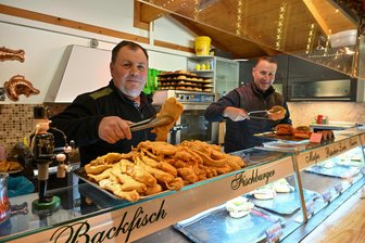 Backfisch, Lachsbrötchen und Matjes: „Fisch darf auf dem Weihnachtsmarkt nicht fehlen“ - Udo Klemm (links), liebevoll „der Fischmann“ genannt, und Schwager Mike Kieller sind mit „Klemms Fischinsel“ zum Weihnachtsmarkt unweit der Hauptbühne in Chemnitz anzutreffen. „Fisch geht immer“, sagt der 63-Jährige.
