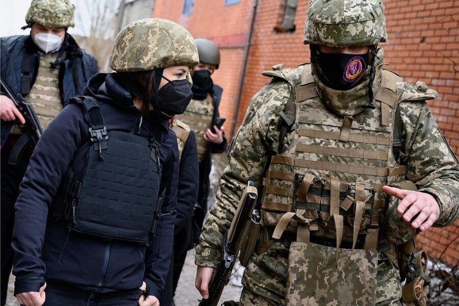 Baerbock zwischen allen Fronten - Mit Schutzhelm und Maske: Annalena Baerbock (vorn links) verschafft sich in der Ostukraine ein Bild von der Lage. 