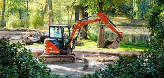 Bagger ebnet Boden für Spielplatzbau - 