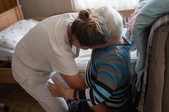 Eine Pflegekraft hilft einer Frau beim Umsetzen.