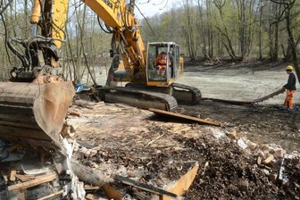 Baubeginn am Maschinenteich: Bagger schafft Platz für Radweg - Am Maschinenteich in Auerbach, unterhalb des Lidl-Marktes, haben die Arbeiten für ein neues Teilstück des Göltzschtal-Radweges begonnen. Im Bild reißen Mitarbeiter des VSTR ein baufälliges Gebäude ab, das der Radweg-Trasse im Weg war.