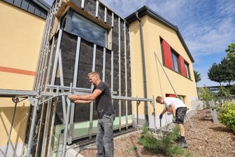 Baukosten laufen aus dem Ruder - Letzte Arbeiten am Hort-Anbau in Ottendorf: Ein Gerüst wird angebracht, um die restlichen Fassadenelemente montieren zu können.