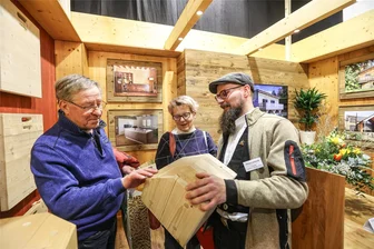 Baumesse Chemnitz 2024: Knapp ein Drittel weniger Besucher als letztes Jahr - Matthias und Andrea Wienhold informieren sich bei Vincent Katterwé (rechts), Mitarbeiter in der Mühlauer Tischlerei und Holzbau Gmbh von Bernd Tischer, über Häuser, die in Holztafelbauweise errichtet werden. Das Ehepaar aus Annaberg-Buchholz möchte sein Haus verkaufen und in ein kleineres ziehen.
