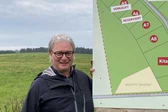 Baurecht für Baugebiet im Vogtland: „Das Interesse speziell in Zwickau ist groß“ - Noch ist überall grüne Wiese, doch schon bald rollt schweres Baugerät an. Investor Markus Lux an der Schautafel zum Baugebiet „Hauptmannsgrüner Straße“ in Irfersgrün.
