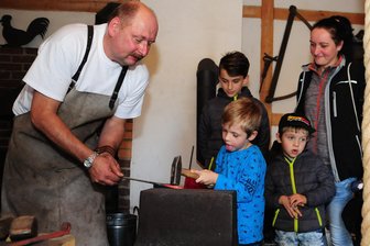 Bei Handwerkern geht's heiß her - Hobbyschmied Jens Langer hatte neugierige Gäste: Susan Rösner aus Marienberg zählte mit ihren Jungs Ryan, Logan und Marlon (v. r.) zu den knapp 500 Besuchern in Lauta.