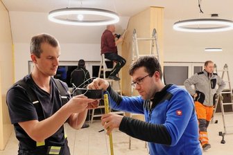 Beierfeld: Feuerwehrleute packen bei Sanierung mit an - Martin Pohlheim und Torsten van Bernum (r.) bei der Montage der neuen Leuchten, im Hintergrund werden die Raumteiler gestrichen.