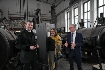 Bergbaumuseum Oelsnitz erhält Millionenbetrag: Kohlewelt soll in einer anderen Liga spielen - Museumsleiter Jan Färber (l.), Staatssekretärin Barbara Meyer und Beigeordneter Andreas Stark an der größten noch funktionsfähigen Dampfmaschine Sachsens. Der Raum ist fast fertig saniert.