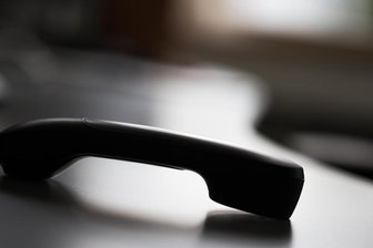 Ein Telefonhörer liegt auf einem Tisch.