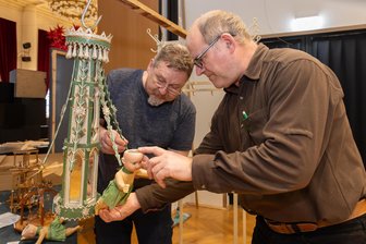 Bevor das Licht im Erzgebirge ausgeht: „Erzhammer“ wird für Ausstellung zum großen Lichterhaus - Volker Krämer (l.) und Jörg Bräuer beim Zusammenbau eines etwa 100 Jahre alten Hängeleuchters mit Engelpuppen. Er wird ab Sonnabend in der Januarausstellung im Annaberger „Erzhammer“ zu sehen sein.