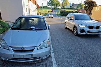 Bierdosen im Getränkehalter, Schlüssel bei der Polizei: Das rätselhafte herrenlose Auto von Lobsdorf - In Lobsdorf an der Glauchauer Landstraße steht seit Mitte August dieser Suzuki. Die Polizei hat das Fahrzeug durch einen Abschleppdienst vom Feld im Bildhintergrund auf die Straße bringen lassen.