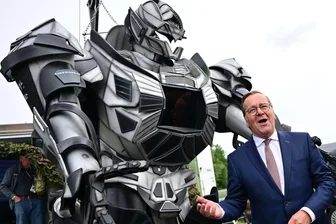 Bilder des Tages vom 12.06.2026 - Verteidigungsminister Pistorius scherzt neben einer Transformer-Figur bei der ILA 2026 in Berlin.