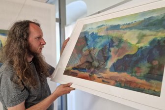Böhmische Impressionen: Ausstellung für Vogtland-Künstler und Grenzgänger - Der Grafiker Mario Schmidt beim Aufbau der Ausstellung „Böhmische Impressionen“. Johannes Wagner hat den Klingenthaler Wald als Aquarell in Szene gesetzt.