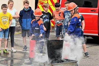 Böhrigen macht Schule: Bei dieser Feuerwehr wird wirklich der Kaffee kalt - Alice und Finn von der Jugendfeuerwehr Böhrigen zeigen hier, wie man mit dem Feuerlöscher einen brennenden Papierkorb löscht.
