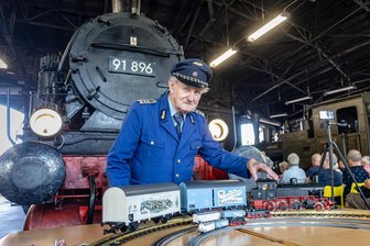 „BR 91.3“: Warum Piko seine neue Modell-Dampflok ausgerechnet in Chemnitz vorstellt - Museumsmitarbeiter Martin Müller präsentiert die neuen Modellversionen der BR 91.3 vor der historischen Dampflok im ehemaligen Bahnbetriebswerk in Chemnitz-Hilbersdorf.