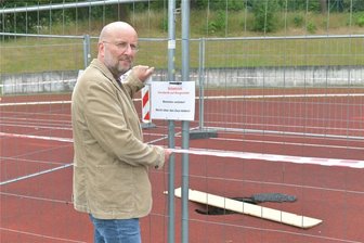 Brand Erbisdorf: Darum ist ein Stück Sportplatz abgesperrt - Dierk Schülke von der Stadtverwaltung Brand-Erbisdorf kontrollierte am Freitag die Absperrung auf dem Sportplatzgelände an der Dammstraße. Im Tartanbelag hat sich ein tiefes Loch aufgetan.