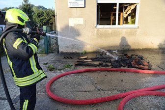 Brand in einer Wäscherei in Schwarzenberg: Feuerwehr verhindert größeren Schaden - Aus dem Brandraum geholte, verkohlte Materialien, darunter Holzteile und Bodenmatten, wurden vor dem Wäschereigebäude noch abgelöscht.
