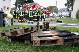 Brand in Netzschkau: Wohnung nicht mehr bewohnbar -  Verkohlte Reste eines aus Europaletten gebauten Bettes, einer Matratze und eines Stuhles lagerten vor dem Gebäude an der Netzschkauer Walter-Rathenau-Straße. Ein Brandursachenermittler nahm noch am Abend dort die Arbeit auf.