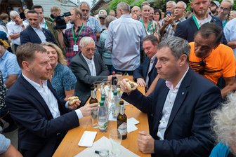 Bratwurst-Politik: Was Markus Söder und Michael Kretschmer in Blockhausen im Erzgebirge wirklich gesagt haben - Michael Kretschmer (links) und Markus Söder (rechts) ließen sich in Blockhausen eine Bratwurst schmecken. Neben Kretschmer sitzt Gastgeberin Steffi Martin.
