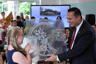 Brückenberg-Schule in Schwarzenberg nach Sanierung offiziell übergeben - Statt eines Schlüssels gab es zur offiziellen Einweihung der sanierten Brückenberg-Schule in Schwarzenberg von Landrat Rico Anton ein Namensschild der Schule, das Anika entgegen nehmen durfte.