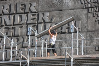 Brückenstraße Chemnitz: Freistaat saniert prominenten Schriftzug hinter Marx-Monument - Gerüstbauer sind hinterm Nischel am historischen Schriftzug an der Fassade des langen Behördenriegels zu Gange.