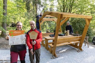Bürgermeister einer Stadt im Erzgebirge löst seine Wettschulden ein - Bürgermeister Thomas Mauersberger (2. v.) - hier im Bild mit Kirsten Drechsel (Öffentlichkeitsarbeit), Jeremias Mai (Bauverwaltung & Technisches Gebäudemanagement) sowie Carsten Schubert (Fachbereich Bauverwaltung) - beim Arbeitseinsatz im Stadtpark. Er zeigt eine alte Gehölztafel.