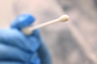 Ein Arzt hält einen Tupfer, mit dem ein Abstrich für einen Coronatest gemacht wird.