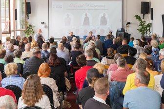 Bürgermeisterwahl Lengenfeld: Kandidaten-Triell sorgt für Rekord-Kulisse - Für das Triell wurden sogar Bänke in den Saal getragen - Vincent Aue, Susann Löffler und Michael Heuck auf dem Podium.
