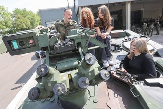 Bundeswehr wirbt in Chemnitz um Nachwuchs: Von verteidigungsbereit bis kriegstüchtig - Mit Tarnschminke auf einem Transportpanzer: Lara Berkholz, Melanie Karasek und Rosalie Otto aus Mittweida lassen sich vor der „Pop-Up-Karrierelounge“ der Bundeswehr in Chemnitz die Technik erklären.