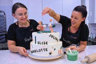Bunt, süß, individuell: So teuer sind Torten zum Schulanfang in Chemnitz - Siselia Mädler (links) und Janette Graf von der Firma "Einzelstücke" bei den letzten Dekorationsdetails für eine Torte zum Schulanfang.
