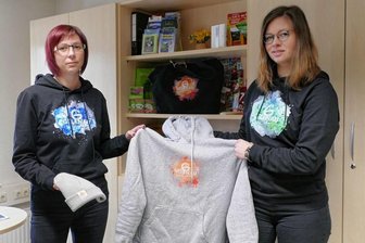 Bunte Farbtupfer läuten die Gelenauer 750-Jahr-Feier ein - Nancy Müller (links) und Stephanie Wolf präsentieren einige der Kleidungsstücke, die im Zuge der Gelenauer750-Jahr-Feier zu haben sind. Erste Bestellungen liegen der Gemeinde bereits vor.