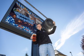 Burgstädt feiert erstmals Oktoberfest mit Haxe, Bier und Musik: Wie die Reithalle zur kleinen Wiesn werden soll - Pascal Köhler steht mit den Utensilien für das Burgstädter Oktoberfest vor einem Großplakat.