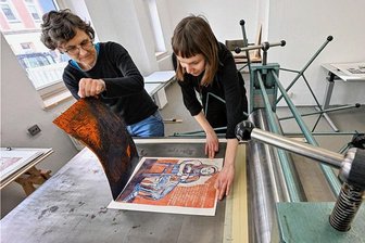Chemnitz macht Druck - eine neue Kreativwerkstatt öffnet - Die Künstlerin Bettina Hain (links) probiert einen zweifarbigen Linolschnitt auf der Druckpresse aus. Werkstattleiterin Selina Müller vom Klub Solitaer assistiert ihr bei der Arbeit.
