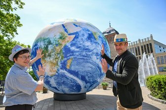 Chemnitzer Hutfestival startet: Mehr Künstler, mehr Platz und eine Reise um die Welt - Linda Lomozová vom „V.O.S.A. Theatre“ in Prag mit C3-Geschäftsführer Ralf Schulze an einem Ballon in Form der Erde.