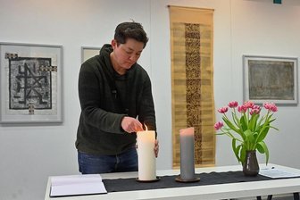 Chemnitzer Künstlerbund: Ein stiller Abschied von fünf bedeutenden Mitgliedern - Daniela Schleich, Mitarbeiterin beim Chemnitzer Künstlerbund, entzündet in der Ausstellung, die verstorbenen Künstlern gewidmet ist, eine Kerze. Im Hintergrund sind Arbeiten von Fritz Schönfelder zu sehen. 