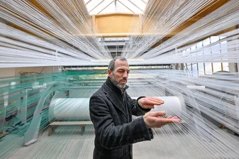 Chemnitzer Unternehmen bringt Schneevergnügen in Europas Städte - Jens Reindl, Geschäftsführer der Firma Mr. Snow, zwischen 12.000 Kunststofffäden, die in eine Webmaschine führen.