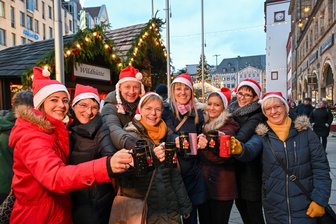 Chemnitzer Weihnachtsmarkt eröffnet: Was kosten Glühwein, Roster und Dubai-Schokolade - Eine Gruppe Besucher aus Altenburg stößt zur Eröffnung mit Glühwein an.