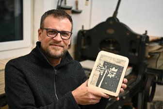 Chursdorfer Künstler René Pützschel: Tierarzt am Tag, Maler und Grafiker in der Nacht - Künstler René Pützschel in seinem Atelier in Chursdorf: Der Künstler zeigt an der Druckpresse einen Lithografiestein. Der Steindruck hat es dem 52-Jährigen ganz besonders angetan.