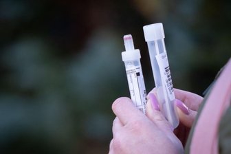 Corona: Die Lage im Vogtland am Dienstag - Eine Frau hält Teströhrchen für einen Abstrichtest und eine Blutprobe in den Händen (Symbolbild).