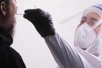 Ein Helfer nimmt einen Abstrich für einen Corona-Test.