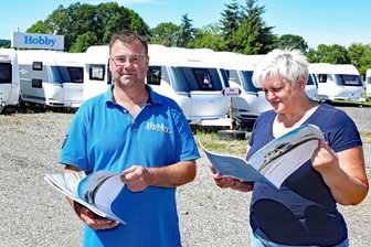 Corona lässt Wohnmobil-Geschäft boomen - Thomas und Sandra Scheibe vom Caravanzentrum Spitzner in Schönfels haben derzeit Reisemobile lediglich zum Anschauen in Prospekten. Die Wohnanhänger im Hintergrund gehen kommende Woche alle vom Hof. 